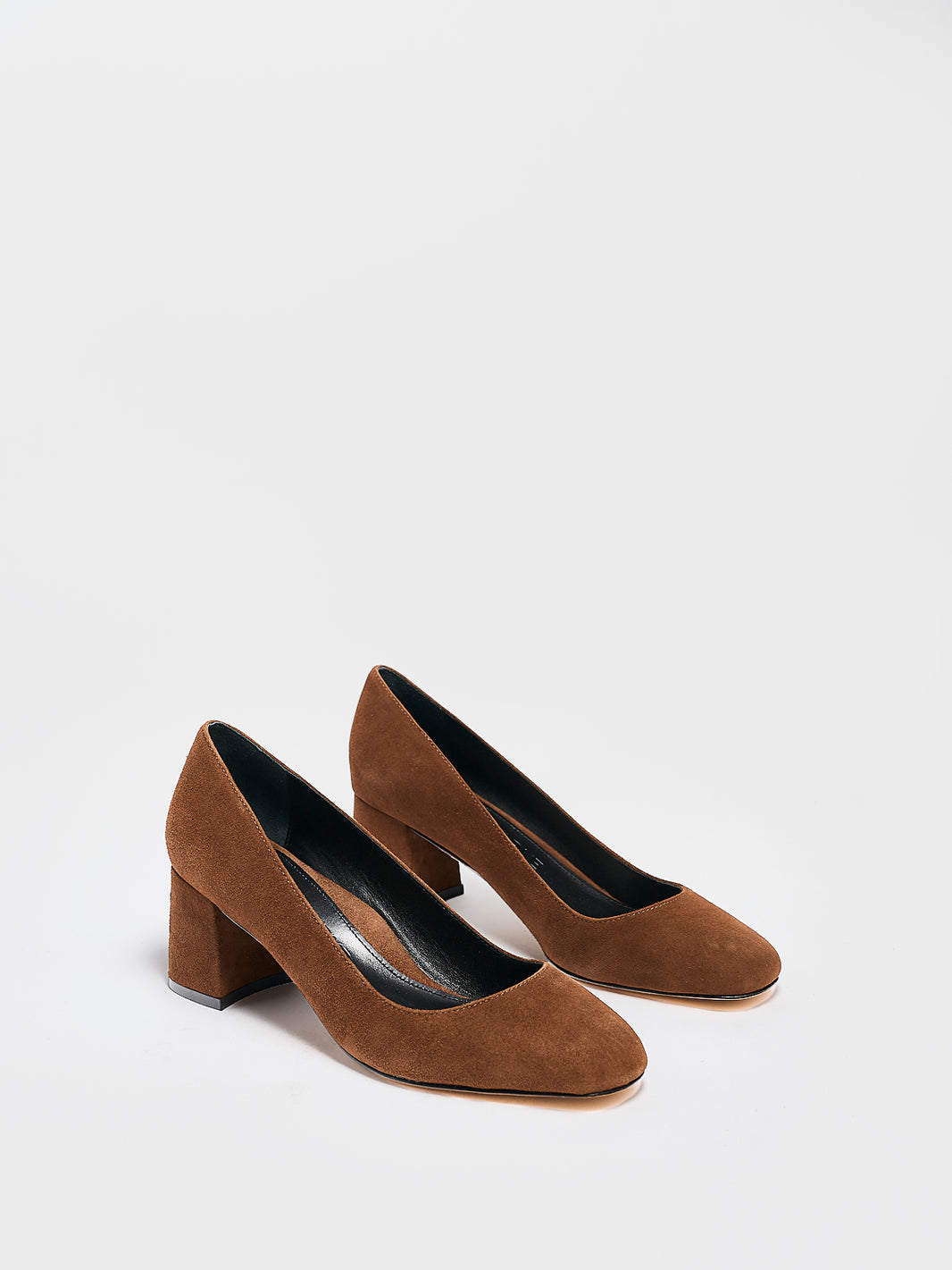 Angle view of a pair of mocha brown suede block heel pumps with a rounded toe.