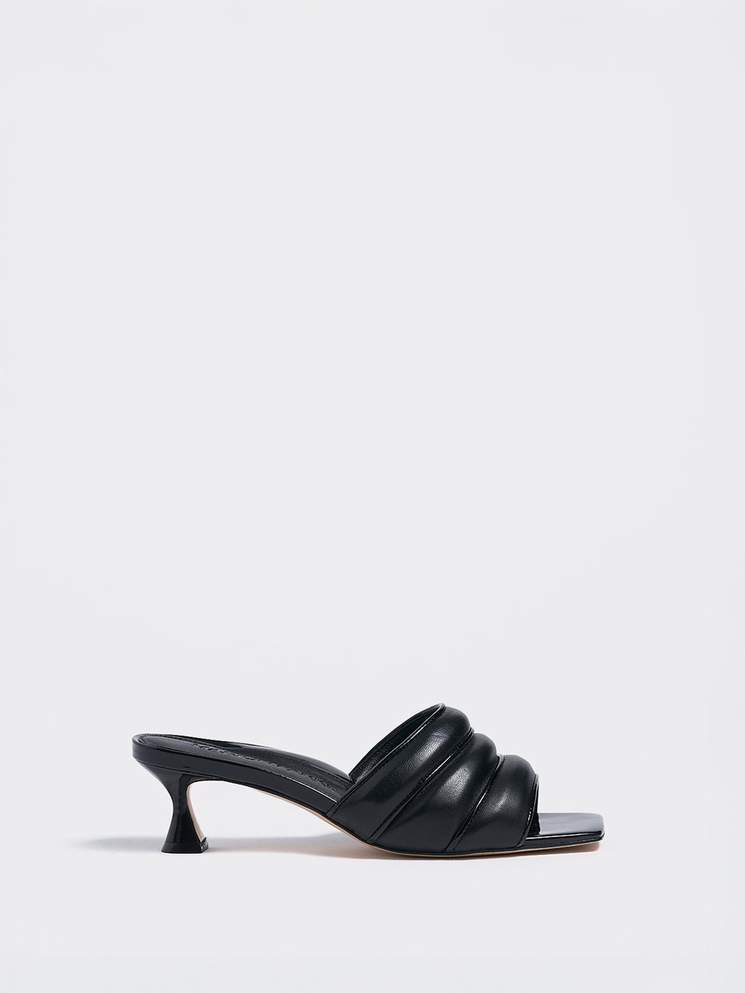 Profile view of a black leather slide kitten heel with a patent leather trimmed puffy strap detail.