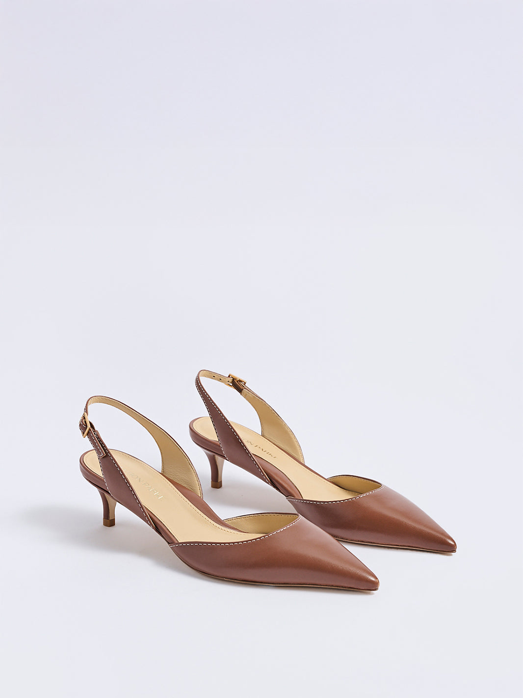 Angle view of a pair of luggage leather slingback heels with a pointed toe
