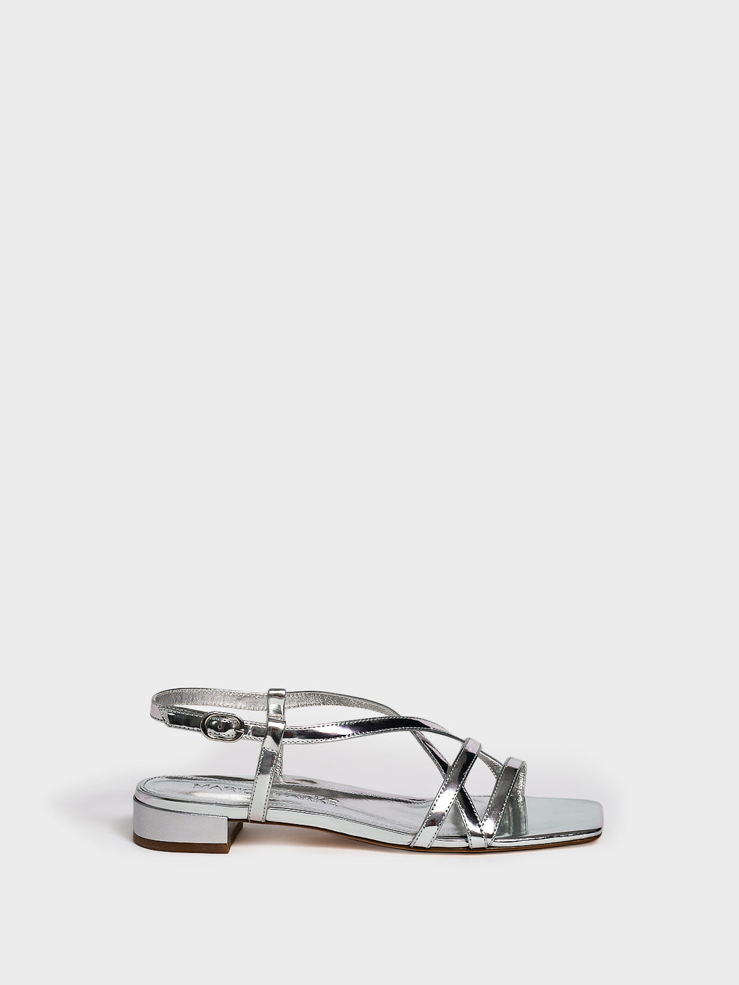 Profile view of a silver metallic leather flat strappy sandal.
