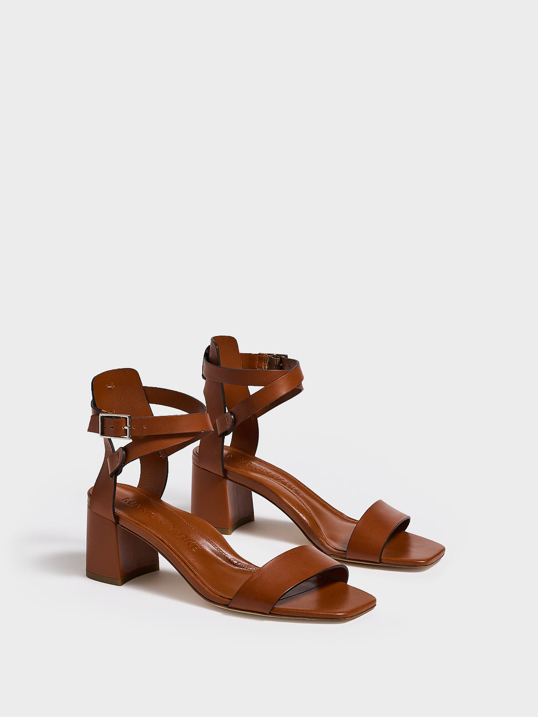 Angle View of a pair of chestnut leather block heel sandals with an adjustable ankle strap design.