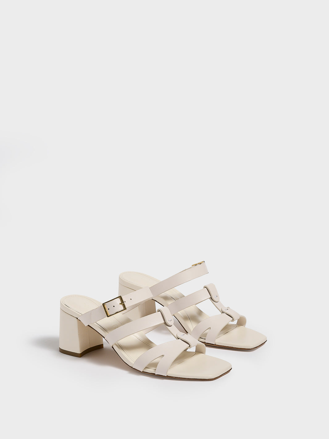 Angle view of a pair of ivory leather gladiator block heel sandals.