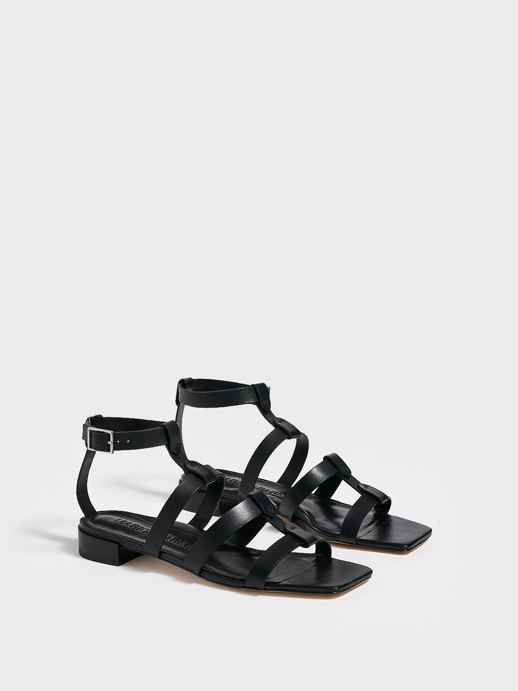 Angle view of a pair of black leather gladiator sandals with an adjustable ankle strap.