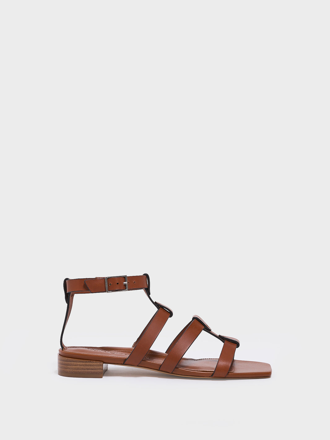 Profile view of an chestnut leather gladiator sandal with an adjustable ankle strap.