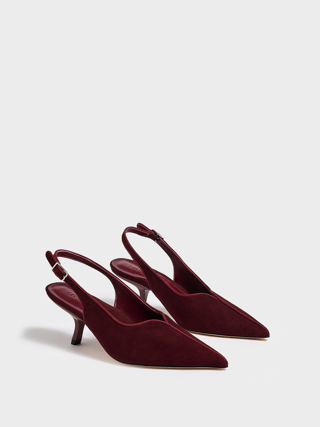 Angle view of a pair of burgundy  leather slingback kitten heels with a grosgrain trim and angled heel detail.