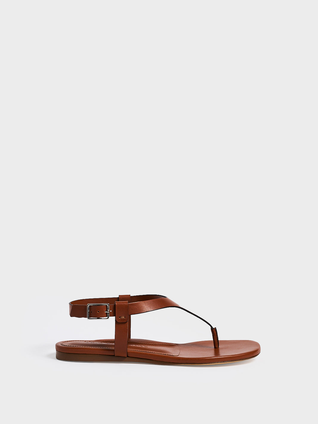Profile view of a chestnut leather thong sandal with a clean design and adjustable ankle strap. 